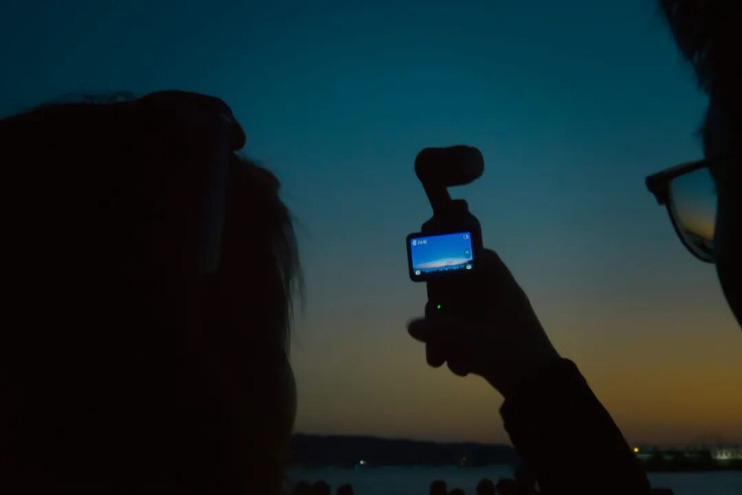 人们用小相机拍摄日落。